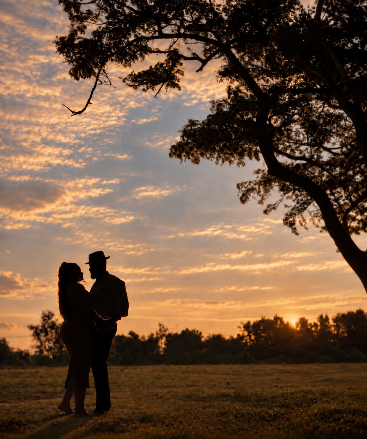 Jeffrey and Bridget facing one another beneath a tree at sunset